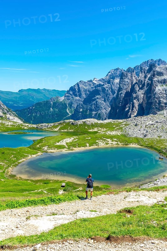Tourist taking photos of the breathtaking landscape of the tre cime di lavaredo and the turquoise lake in the italian dolomites during summer. Laghi dei Piani