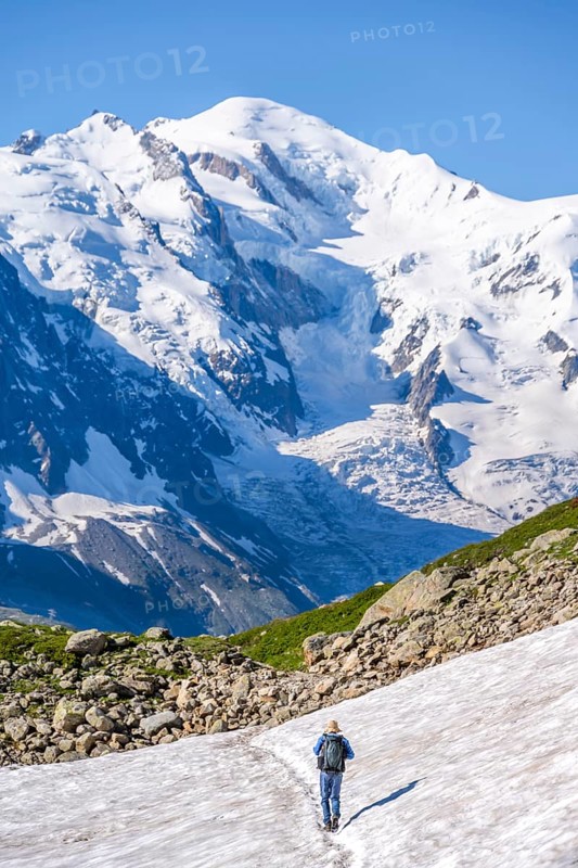 Mountaineer crossing a snowfield, view of spectacular glaciated peaks of Mont Blanc, Mont Blanc massif, Aiguilles Rouges, Chamonix-Mont-Blanc, Haute-Savoie, France
