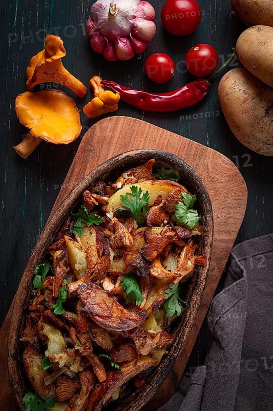 Fried chanterelles with potatoes, in a clay frying pan, top view, homemade, no people