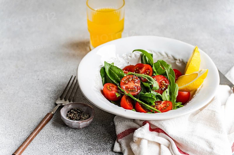 A vibrant salad featuring fresh arugula and herbs, cherry tomatoes, and seeds, drizzled with olive oil and Himalayan salt. Perfect for a healthy, flavorful meal