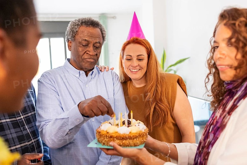 A joyful birthday celebration with friends gathered around a cake. The atmosphere is filled with happiness, as people share smiles and moments of togetherness