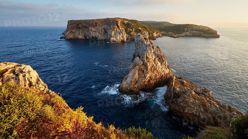 Dramatic cliff landscape surrounded by deep blue sea and waves, morning light, Tsichli Babas islet, Navarino Bay, Pylos, Peloponnese, Greece