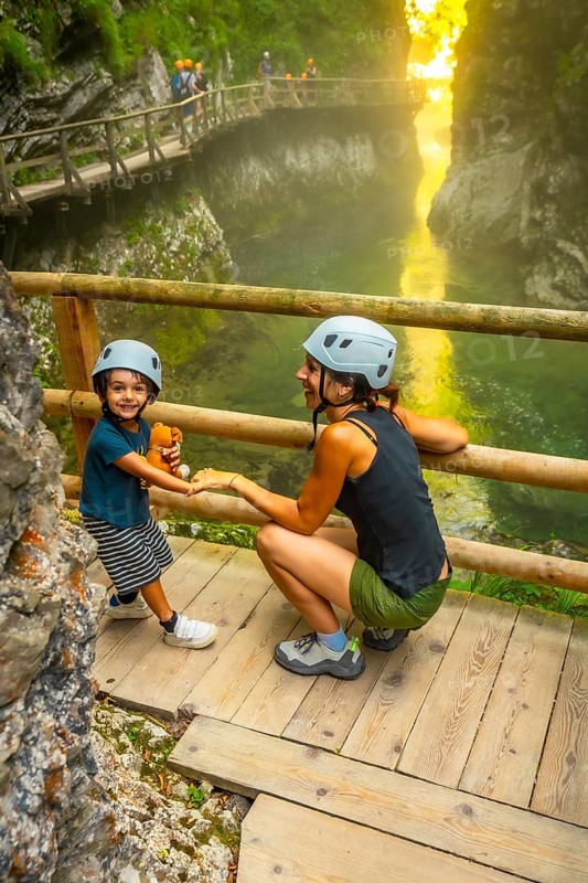 Mother and child wearing helmets enjoying the stunning scenery of vintgar gorge near bled, slovenia, during summer