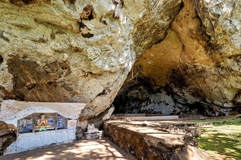 Extensive cave with relief-like wall structure, a small altar on the side, The Batadombalena cave temple near Ratnapura in Sri Lanka
