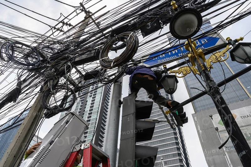 A local Thai engineer working with a tangled web of wires and cables at a set of traffic lights in central Bangkok, capital of Thailand