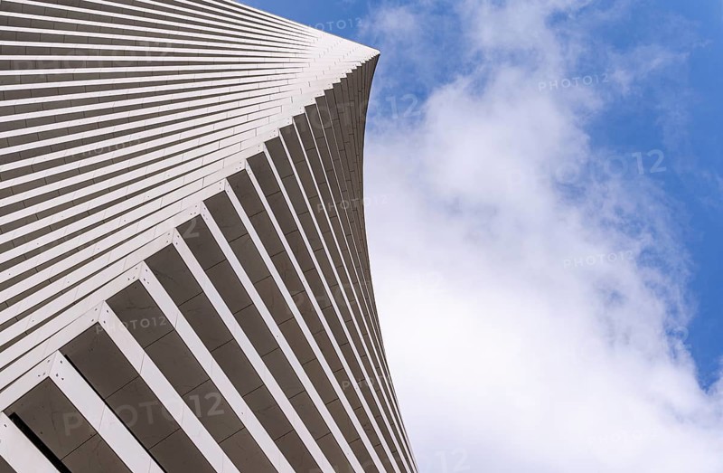 Angular view of a modern building's facade with sleek lines against a bright sky. The unique architectural design highlights dynamic geometry and contemporary aesthetics