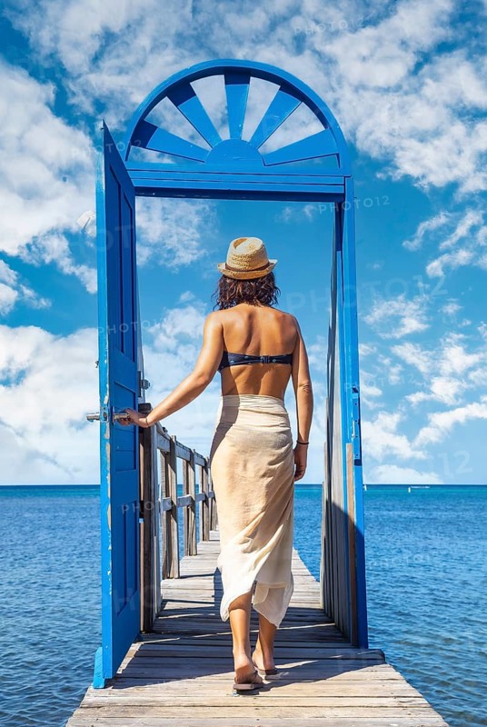 A young brunette passing a blue door in the Caribbean Sea on Roatan Island. Honduras