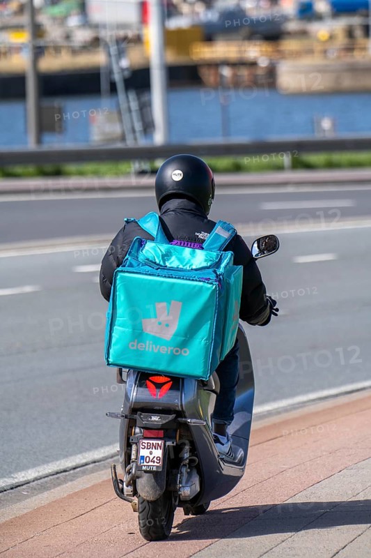 Food, food delivery service Deliveroo rider on moped in Antwerp, Flanders, Belgium