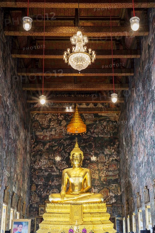 Golden Buddha statue, Phra Buddha Trilokachet, surrounded by exquisite murals, interior view of the Phra Ubosot or ordination hall, Wat Suthat Thepwararam, Royal Temple, Phra Nakhon, Bangkok, Thailand
