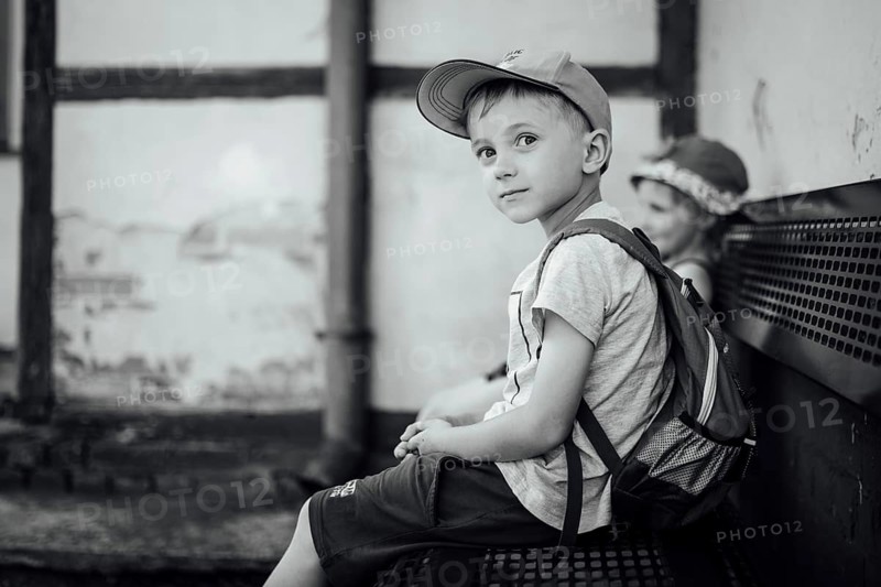 Boy and girl waiting on the bench for a train during warm summer day