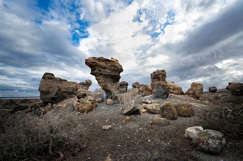 Eroded rock formations in volcanic landscape with dramatic cloudy skies, Ciudad Estratificada or Los Roferos, Antigua Rofera de Teseguite, Lanzarote, Canary Islands, Spain
