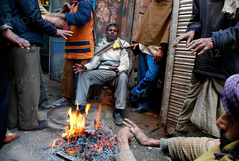 New Delhi, India, 15.01.10 - Traders and workers warm up by a fire at the market in New Delhi, India
