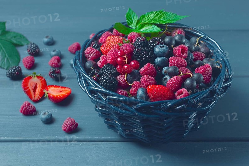 Mix of fresh berries, in a basket, on a wooden gray table, no people, top view