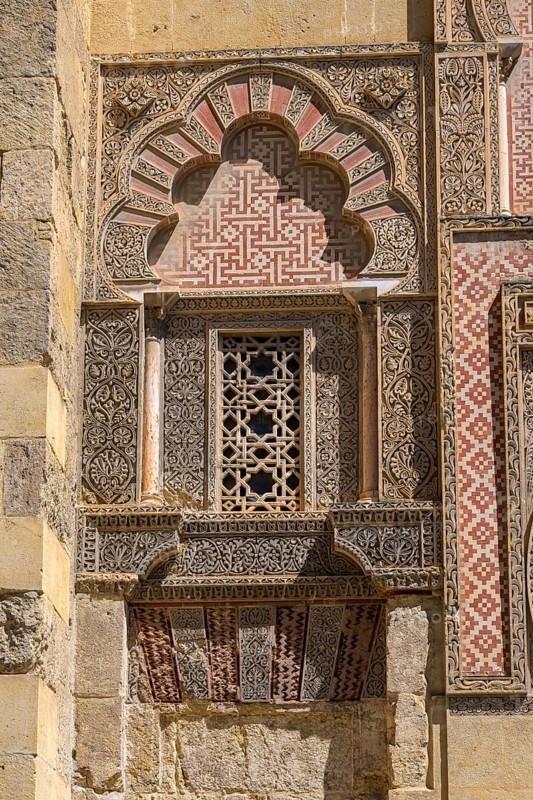 Cathedral Mosque of Córdoba, Mezquita-Cathedral, detailed Islamic architecture with complex patterns and warm colors, detail of a Moorish façade with ornate patterns and arches in red and beige, Cordoba, Andalusia, Spain