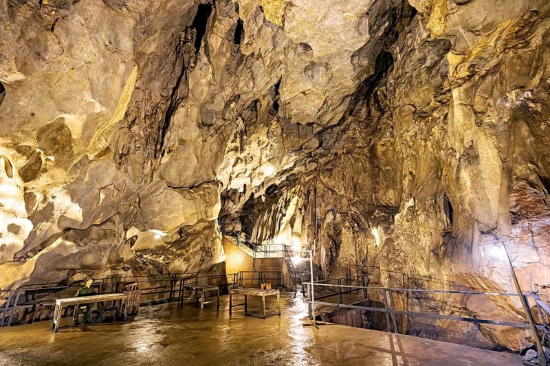 An illuminated cave with impressive rock formations and wet surfaces, The Hospital Cave on Cat Pa Island in Halong Bay, Vietnam