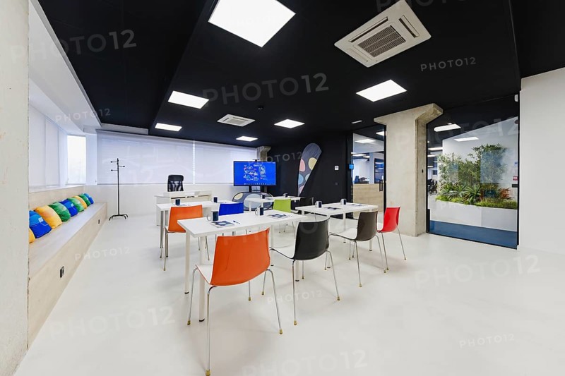 Spacious training room featuring white tables, colorful chairs, and advanced technological facilities, suitable for educational workshops or corporate training sessions