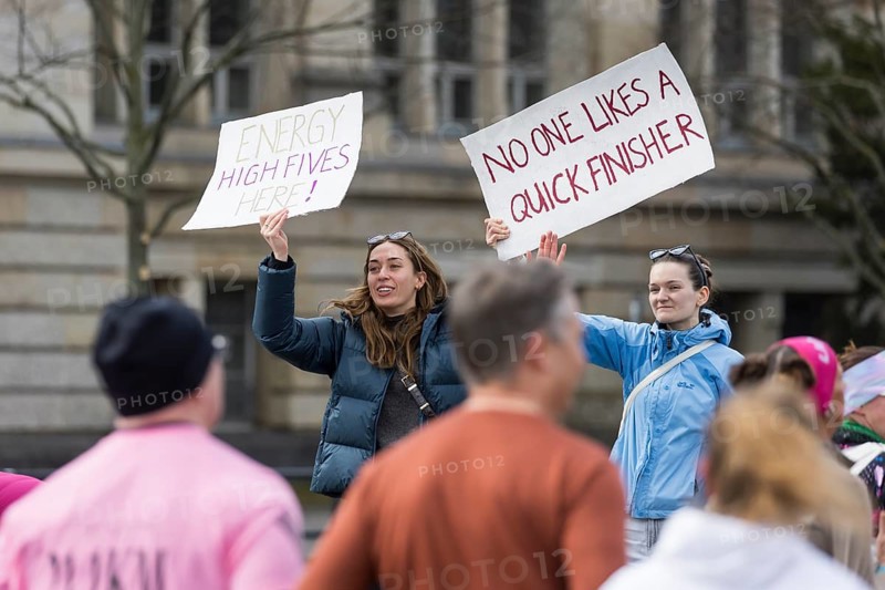 Two woman cheer on runners with signs at Energy High Fives here! and No one likes a quick finisher on Otto-Suhr-Allee at the 45th Generali Berlin Half Marathon 2026 in Berlin on 29.03.2026