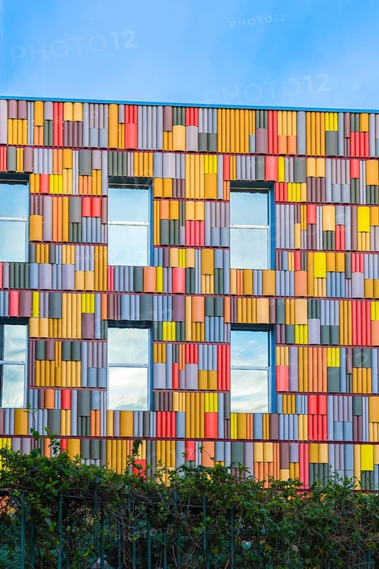 A striking view of a contemporary building featuring a multicolored facade with geometric patterns and vibrant hues, set against a clear blue sky