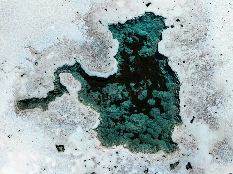 An aerial view of the stunning salt ponds in La Puna, Argentina, showcasing their unique turquoise and white patterns set against the natural landscape