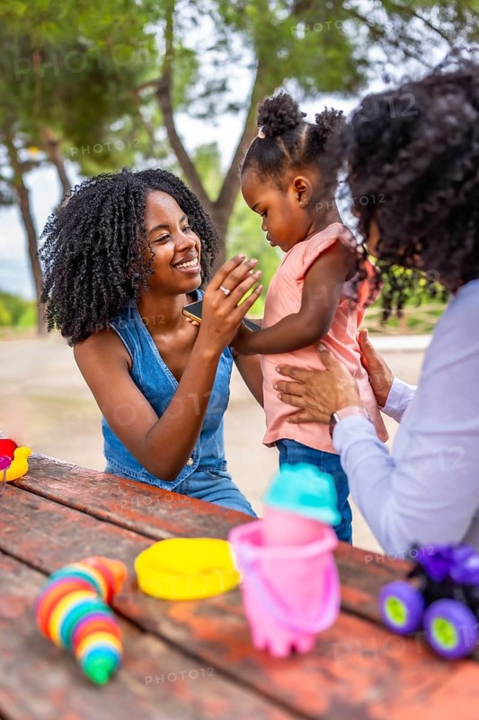 Vertical photo of happy family time in the park with african toddler girl