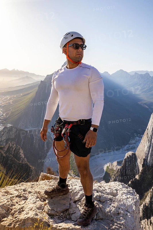 A man gears up for an adventurous day of mountaineering and rappelling against the stunning backdrop of Eagleâ€™s Nest in Monterrey, Mexico, showcasing his climbing equipment