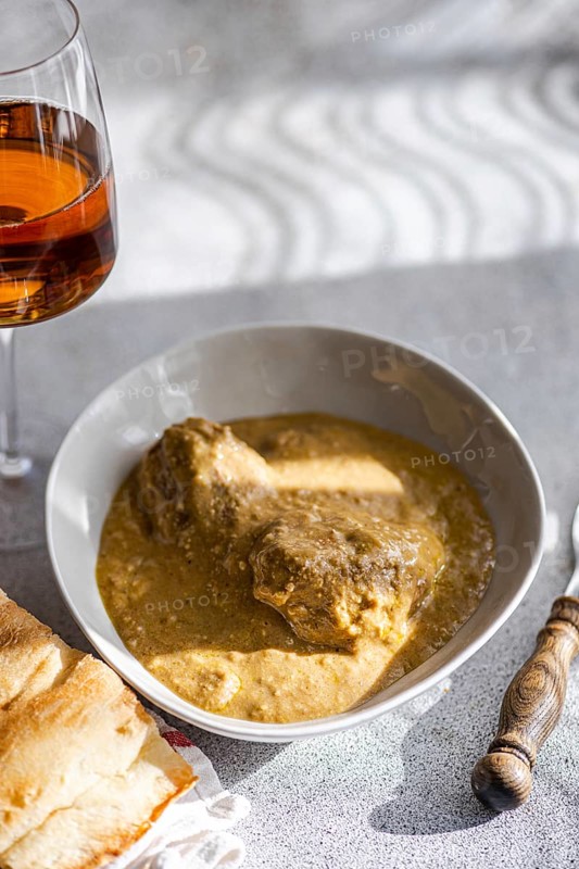 From above a classic Georgian dish, satsivi, featuring chicken in a rich walnut sauce, elegantly paired with a glass of rare amber wine, served alongside freshly baked bread