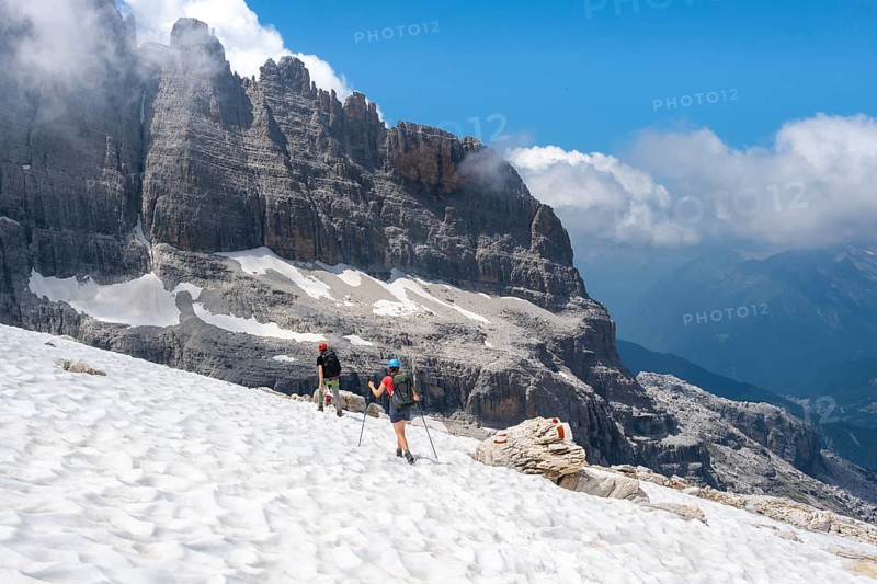 Hikers on hiking trail 305 cross a snowfield, Brenta Mountains, Parco Naturale Brenta-Adamello, Trentino, Italy