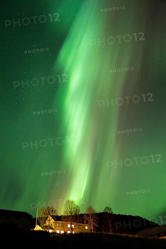 Intense northern lights (aurora borealis) over an illuminated house, Alvdal, Hedmark, Innlandet, Norway, October 2025