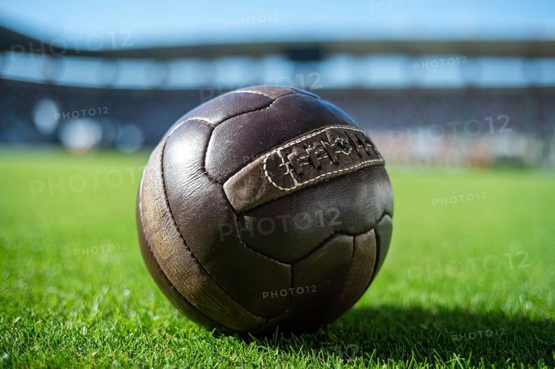 Old soccer ball on the grass at the stadium