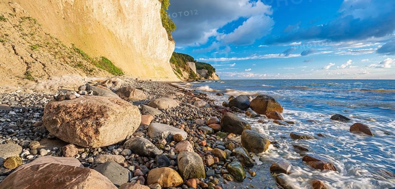 Chalk cliffs and rocky beach with boulders on the Baltic Sea under blue sky with cumulus clouds, Jasmund National Park, Rügen Island, Mecklenburg-Western Pomerania, Germany