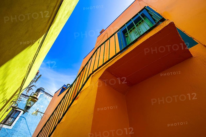 From below colorful buildings of Guanajuato, Mexico, illustrating the vivid colonial architecture with a mix of bright blue, yellow, and orange hues