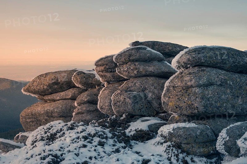 Captivating view of snow-dusted rock formations in Siete Picos, located in the scenic Guadarrama Mountains, Madrid. The soft golden sunset enhances the serene beauty