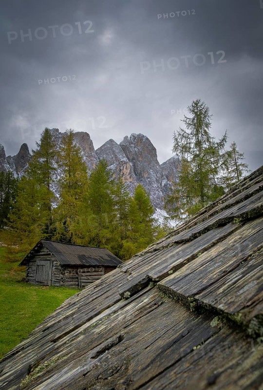 View over a wooden roof of a mountain hut to a part of the Geisler group from the Gampenwiese, Dolomites, snow, Puez-Geisler nature park Park, St. Magdalena, Funes, Villnößtal, South Tyrol, Italy
