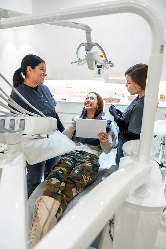 Patient holding a tablet while discussing treatment options with dentists in a modern dental clinic, fostering open communication and care