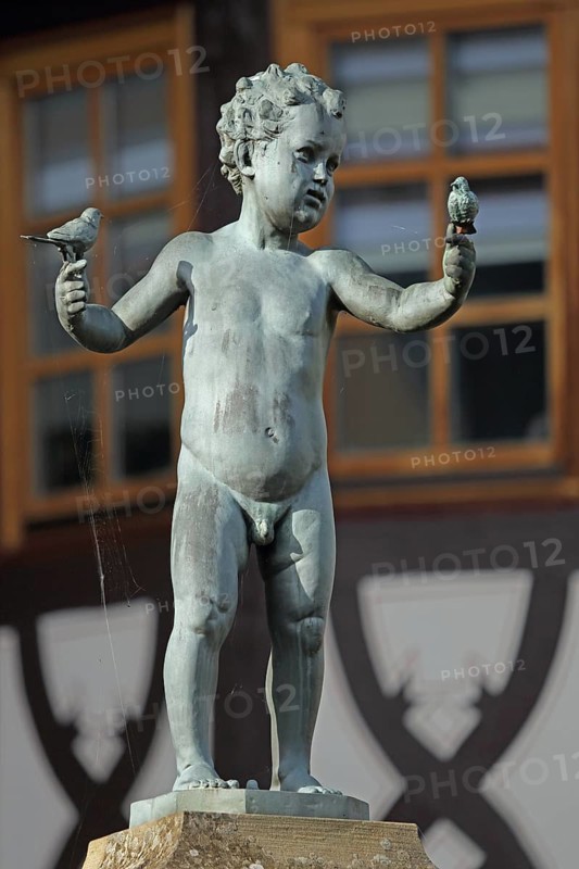 Sculpture Boy with two bird figures holding hands by Emil Cauer 1938, putto, heraldic animal, heraldic bird, naked, arms, Paridae, stretched, looking, watching, holding, caring, protecting, fountain, Rapportierplatz, Meisenheim, Rhineland-Palatinate, Germany