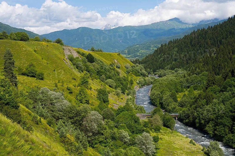 Idyllic landscape with a river flowing through green mountains and forests under clear skies, Tskheniszqali River near Jakhunderi, Racha-Lechkhumi region and Lower Svaneti, High Caucasus, Georgia