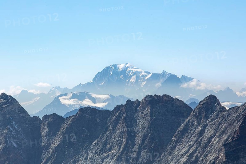 Stunning view of Zermatt's rugged mountains under a clear blue sky, featuring snow-capped peaks and distant glaciers in summer, perfect for hikers and nature enthusiasts