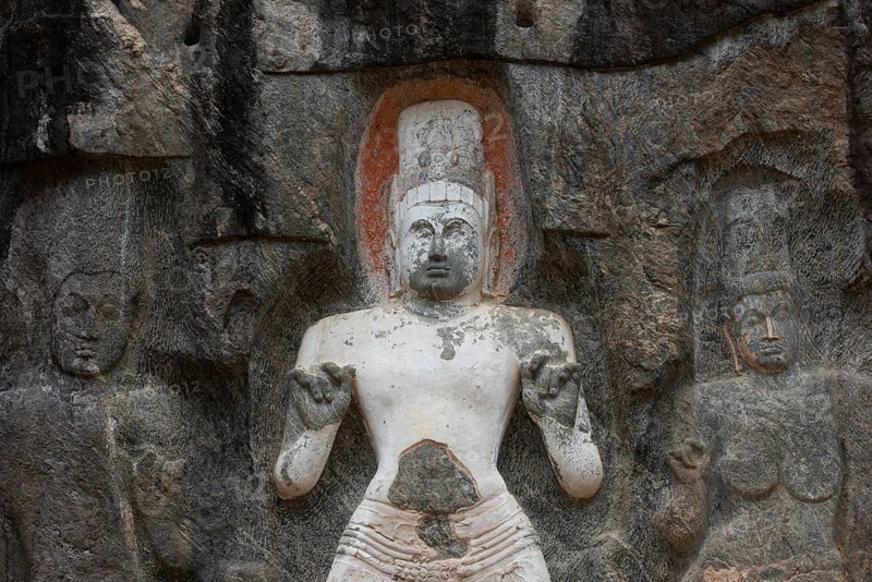 Detailed rock carvings depict sacred figures in Sri Lanka, showcasing intricate artistry and spiritual significance. The carvings evoke a sense of ancient history and culture