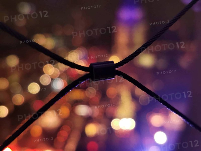 Abstract bokeh view at night with blurred lights and a wire fence in the foreground, lights of the Christmas market at Gendarmenmarkt in the background, Berlin