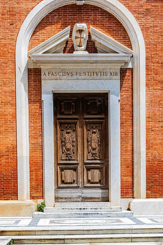 Decorated arched entrance gate in a brick façade, Pisa, Tuscany, Italy
