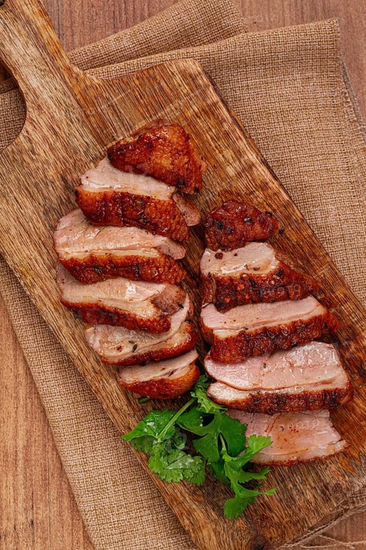 Roast duck breast, sliced, on a wooden chopping board, close-up, no people
