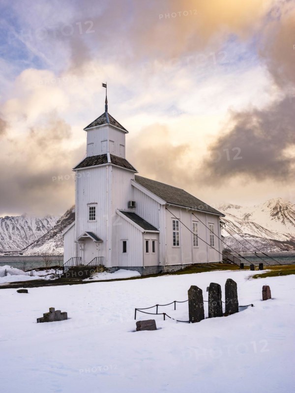 Gimsøy church with cemetery, snow-covered mountains in the background, winter, Gimsøya, Lofoten, Norway