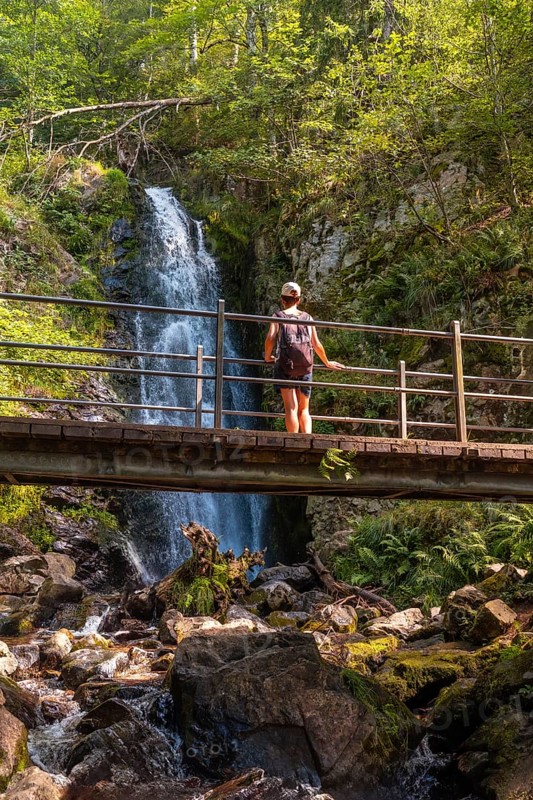 A woman on the upper part of a wooden bridge at the Todtnau waterfall in the Black Forest in Germany