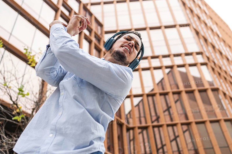 A Cuban man in headphones dances energetically, filled with rhythm, against an urban backdrop. His expression embodies joy and passion for music and movement