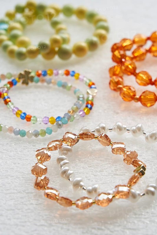 Assorted handmade beaded bracelets showcasing colorful and diverse bead patterns on a white textured surface, highlighting artisan jewelry craftsmanship