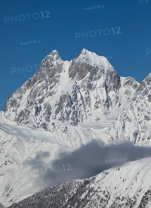 Breathtaking view of a majestic mountain peak covered in snow, set against a clear blue sky in Georgia The stunning scene is perfect for nature and winter enthusiasts alike