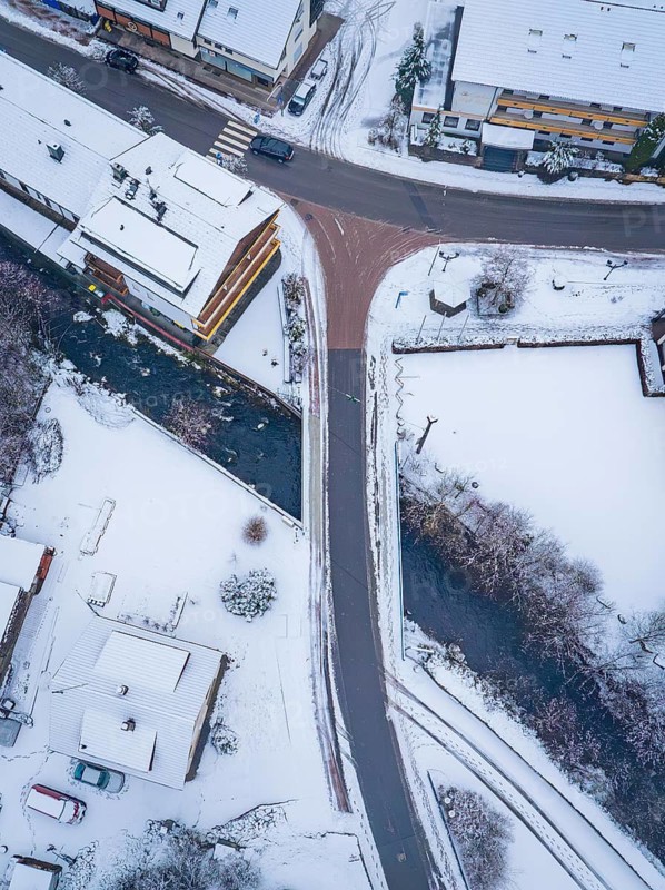 Snowy crossroads in a small village with neighbouring river, Enzklösterle, district of Calw, Black Forest, Germany