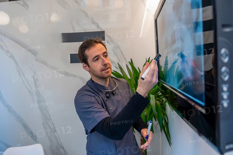 Dentist explaining a dental radiography using a digital screen in a modern and bright clinic