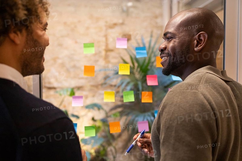 Two individuals engage in a brainstorming session surrounded by colorful sticky notes in a coworking space in Barcelona, fostering creativity and innovation in a modern work environment