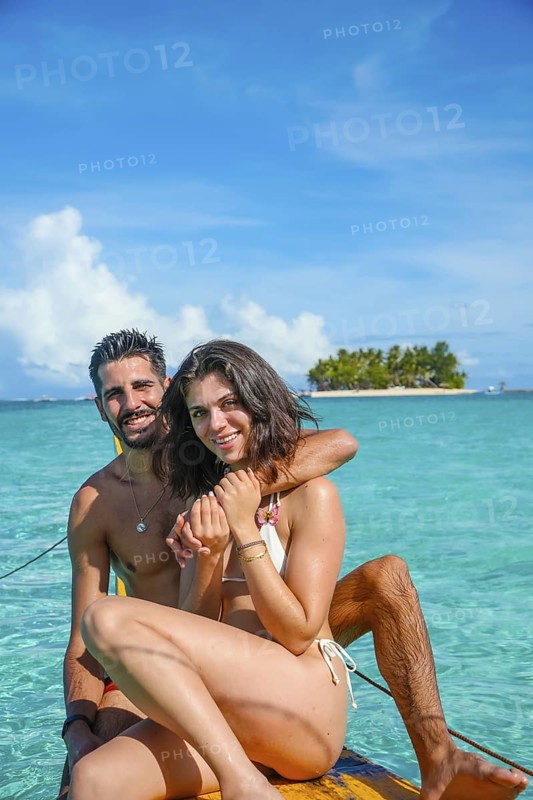 Couple embracing on outrigger canoe, enjoying crystal clear turquoise water of guyam island in philippines